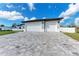 Paver driveway leading to a spacious three-car garage with white doors, set against a manicured lawn at 5322 Syracuse Rd, Venice, FL 34293