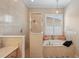 Bright bathroom with a soaking tub, shower, neutral tile, and a window with plantation shutters at 5412 Royal Poinciana Way, North Port, FL 34291