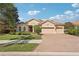 Charming home featuring a tile roof, three-car garage, and manicured landscaping under a sunny sky at 5412 Royal Poinciana Way, North Port, FL 34291