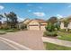 Exterior view of a beige home with a brick driveway, manicured landscaping, and a three-car garage at 5412 Royal Poinciana Way, North Port, FL 34291