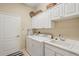 Functional laundry room with white cabinets, sink, and modern washer and dryer at 5412 Royal Poinciana Way, North Port, FL 34291