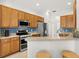 Well-lit kitchen with stainless steel appliances, wood cabinetry, and breakfast bar with seating at 5907 90Th Avenue E Cir, Parrish, FL 34219
