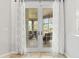 View of an enclosed patio through French doors with decorative curtains at 5907 90Th Avenue E Cir, Parrish, FL 34219