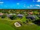 Picturesque aerial view of homes in a golf community with mature trees, lush lawns, and an inviting sand trap at 600 Eagle Watch Ln, Osprey, FL 34229