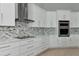 White kitchen cabinets with stainless steel appliances and mosaic backsplash at 600 Eagle Watch Ln, Osprey, FL 34229