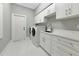Well-appointed laundry room with white cabinets, counterspace, and modern appliances at 600 Eagle Watch Ln, Osprey, FL 34229