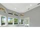 Living room with large arched windows, tray ceiling, and access to the outdoor living space at 600 Eagle Watch Ln, Osprey, FL 34229