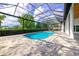 Screened-in pool area featuring a refreshing pool and spa surrounded by lush landscaping and stylish stone pavers at 600 Eagle Watch Ln, Osprey, FL 34229