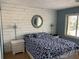 Cozy bedroom featuring plank accent wall, a stylish mirror, and side tables at 6703 Midnight Pass Rd # 206, Sarasota, FL 34242