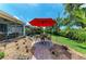 Charming backyard patio with a red umbrella and landscaping, perfect for outdoor entertaining at 736 Rosemary Cir, Bradenton, FL 34212