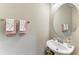 Bright powder room featuring a pedestal sink, round mirror, and floral-themed hand towels at 736 Rosemary Cir, Bradenton, FL 34212