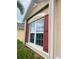 Close up of exterior showing a window with dark red shutters at 7508 Mikasa Dr, Punta Gorda, FL 33950