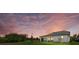 Back exterior of home featuring a lawn and covered patio dining area, with a sunset sky at 7765 Grande Shores Dr, Sarasota, FL 34240