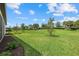 Expansive backyard with a lush green lawn, trees, and well-manicured landscaping at 7765 Grande Shores Dr, Sarasota, FL 34240
