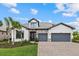 Charming two-story home with a two-car garage, stone accents, lush landscaping, and a brick paver driveway at 7765 Grande Shores Dr, Sarasota, FL 34240