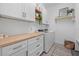 Bright laundry room with white cabinets, wood counters, and modern washer and dryer at 7765 Grande Shores Dr, Sarasota, FL 34240