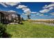Landscaped backyard featuring a screened-in patio overlooking a scenic pond at 8232 Reefbay Cv, Parrish, FL 34219