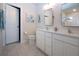 Bright bathroom featuring dual sinks, white cabinets, tile flooring, and coastal-themed wall decorations at 8232 Reefbay Cv, Parrish, FL 34219