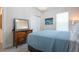 Cozy bedroom showcasing a blue bedspread, wooden dresser, and a serene window view at 8232 Reefbay Cv, Parrish, FL 34219