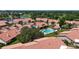 Aerial view of a community with red roofs, mature trees, a pond, and a community pool at 892 Country Club Cir # 50, Venice, FL 34293