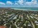 Stunning aerial view of the coastal community with lush greenery and waterways leading to the pristine beach at 105 Island Cir, Sarasota, FL 34242