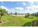 Expansive backyard overlooks a serene lake with a fountain, lush green grass, and palm trees under a cloudy sky at 12570 Brookgreen St, Venice, FL 34293