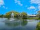 Scenic view of a pond featuring a fountain, mature trees, and a covered seating area for community residents at 1493 Landings Lake Dr # 32, Sarasota, FL 34231