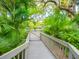 Wooden walkway leading to the community pool amidst lush tropical landscaping with palm trees at 1493 Landings Lake Dr # 32, Sarasota, FL 34231