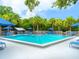 Community swimming pool surrounded by blue striped umbrellas and lush tropical landscaping at 1493 Landings Lake Dr # 32, Sarasota, FL 34231