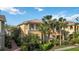 Beautiful two-story townhouse with lush landscaping, palm trees and classic architectural detailing on a sunny day at 1586 Dorgali Dr, Sarasota, FL 34238