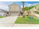 Two story home featuring a two-car garage, neutral stucco, manicured lawn and tropical landscaping with palm trees at 1912 Hawks View Dr, Ruskin, FL 33570