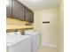 Functional laundry room with washer, dryer, overhead cabinets, and storage shelves at 1912 Hawks View Dr, Ruskin, FL 33570