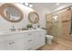 Well-lit bathroom with double vanity, framed mirrors, and glass-enclosed shower at 204 75Th St, Holmes Beach, FL 34217