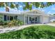 Single-story home with light blue siding, dark shutters, manicured landscaping, and covered porch at 204 75Th St, Holmes Beach, FL 34217