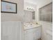 Bright bathroom featuring a single sink vanity, large mirror, and window with blinds at 2551 Waneta Dr, Sarasota, FL 34231