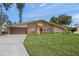 Charming single-story home features a brick facade, well-manicured lawn, and inviting red front door at 2551 Waneta Dr, Sarasota, FL 34231