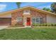 Close up of the home's brick facade with a red front door and beautifully landscaped lawn at 2551 Waneta Dr, Sarasota, FL 34231