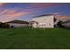The spacious backyard features a lush lawn, and view of a neighboring home at sunset at 3210 Desert Plain Cv, Lakewood Ranch, FL 34211