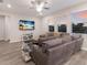 Comfortable living room with a plush gray sofa, a ceiling fan, and large windows providing ample natural light at 3210 Desert Plain Cv, Lakewood Ranch, FL 34211