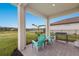 Covered patio with comfortable seating and outdoor grill overlooks the backyard and lake at 3210 Desert Plain Cv, Lakewood Ranch, FL 34211