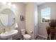 Well-lit powder room featuring a pedestal sink, round mirror, and modern fixtures at 3210 Desert Plain Cv, Lakewood Ranch, FL 34211