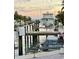 View of a modern boat lift on the canal with a boat, waverunners and the setting sun at 501 Sloop Ln, Longboat Key, FL 34228