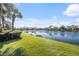 Scenic lake view with lush green grass, palm trees, and charming homes on a sunny day at 5509 Avellino Pl, Sarasota, FL 34238