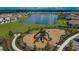 Aerial view of community playground and park with pond and homes nearby in Creek Preserve at 5547 Logan Cave Ave, Wimauma, FL 33598