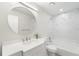 A bathroom features a large, round mirror, modern vanity, and tub with shower at 5689 Evergreen Dr # 18, Sarasota, FL 34233