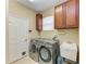 Functional laundry room featuring modern washer and dryer units, cabinets, and utility sink at 643 Misty Pond Ct, Bradenton, FL 34212