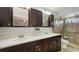 Bathroom with double sinks, cabinets, white countertops and tiled shower with glass door at 6583 Waterford Cir, Sarasota, FL 34238