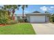 Well-maintained home featuring a lush front yard, mature palm trees, and a spacious two-car garage at 6583 Waterford Cir, Sarasota, FL 34238