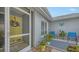 Inviting front porch with a yellow door, blue furniture, decorative butterfly art, and lush green plants at 6583 Waterford Cir, Sarasota, FL 34238