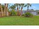 Well-manicured lawn featuring lush landscaping, mature palm trees, and a partial view of the home's facade at 6583 Waterford Cir, Sarasota, FL 34238